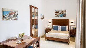 A hotel room with a bed, bedside tables, a desk with a chair, a mirror, and artwork on the walls. - Room in Guest Room - "the 10 Square" - A Townhouse Situated in the Heart of Siggiewi Village Square (Siggiewi)