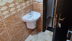 A bathroom with a toilet, sink, and hairdryer on the wall. - Nabateans Home Hotel (Wadi Musa)