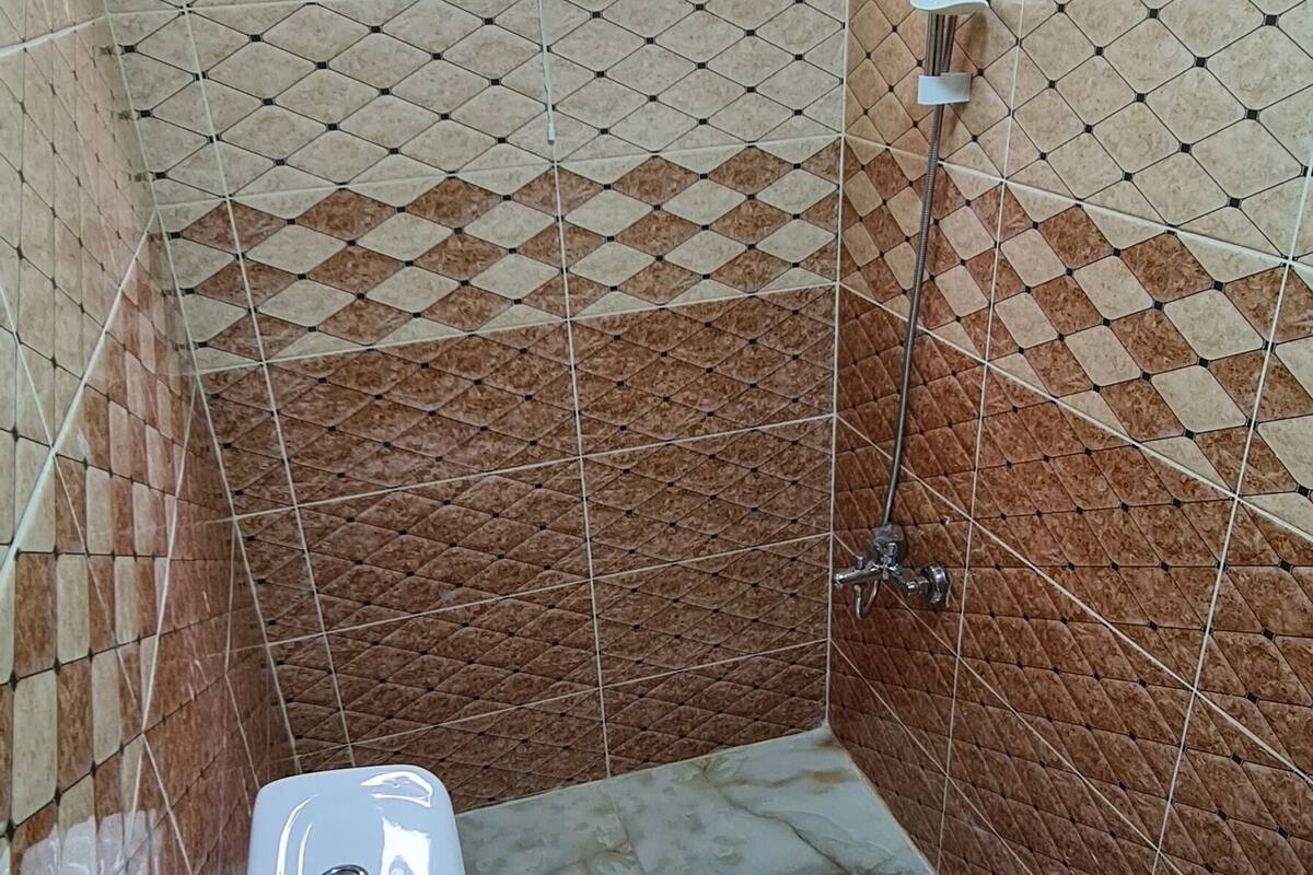 A small bathroom with a toilet, a shower, and a window.