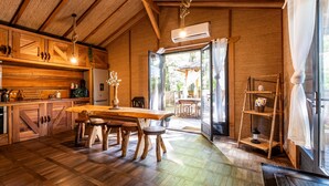 A wooden interior with a dining table, chairs, a kitchen area, and a view through a glass door. - Chalet "Bangli" with Private Terrace and Wi-Fi (LACANAU)