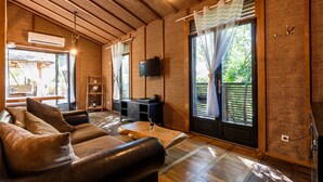 A room with a wooden ceiling, a sofa, a television, and a sliding glass door. - Chalet "Bangli" with Private Terrace and Wi-Fi (LACANAU)