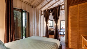 Ein Schlafzimmer mit Bett, Holzwänden, einer Schiebetür und Blick ins Freie.