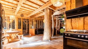 A wooden interior with a kitchen stove, dining table, and chairs.