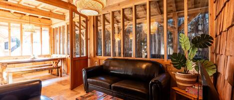 Un interior de madera con un sofá de cuero, un banco, una mesa de centro y una televisión.