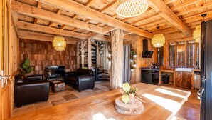 A wooden interior with a sofa, a dining table, and a kitchen area.