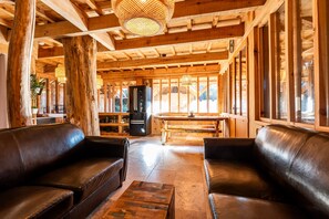 Arredamento in legno con divani in pelle, un tavolo in legno e un frigorifero.