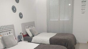A bedroom with two beds, a nightstand, a lamp, and decorative wall art.