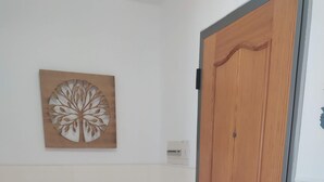 A room with a wooden door, a wall-mounted air conditioning unit, and a decorative wall piece.