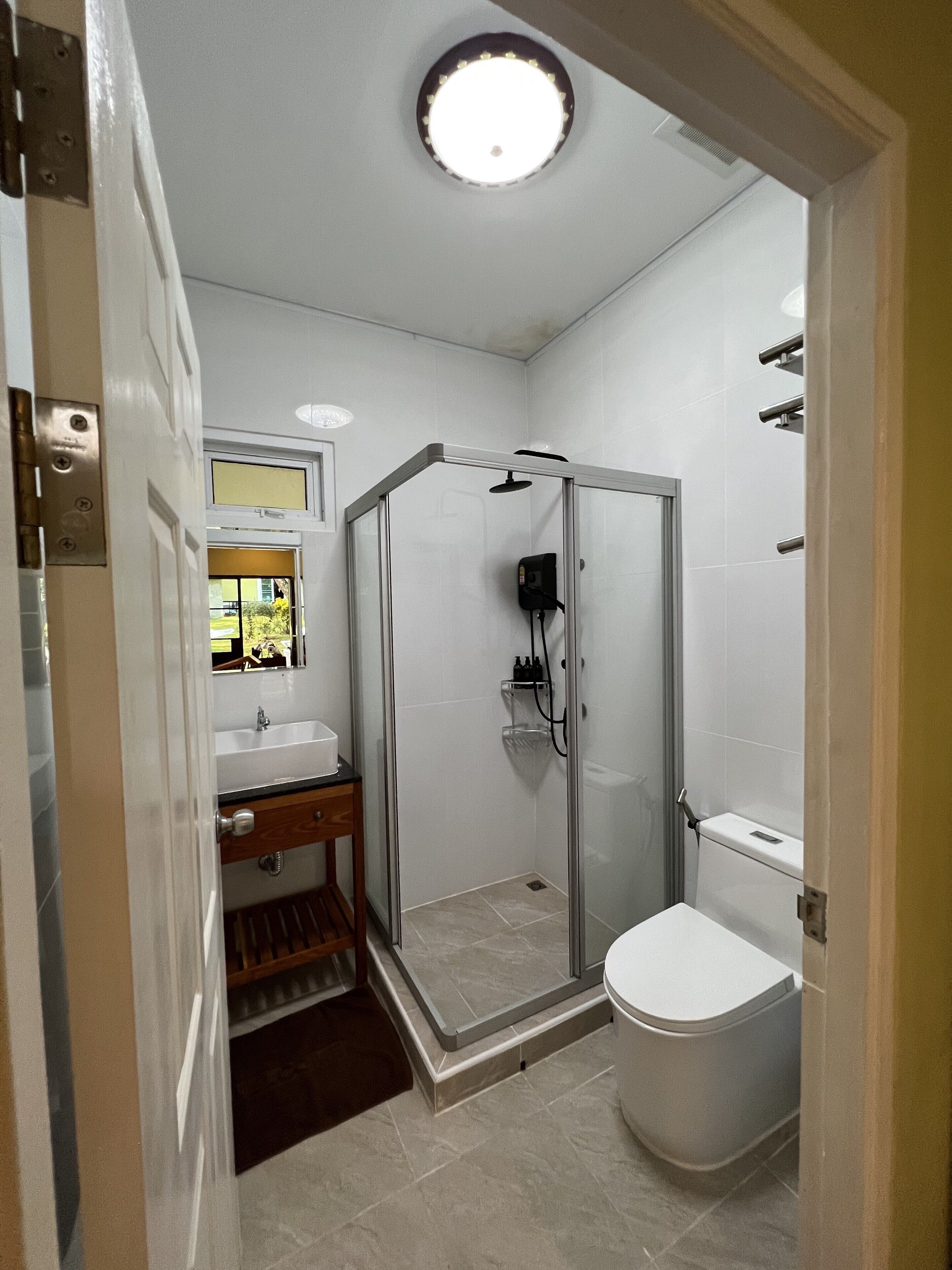 Une salle de bain avec une douche à parois de verre, des toilettes et un lavabo avec un miroir au-dessus.
