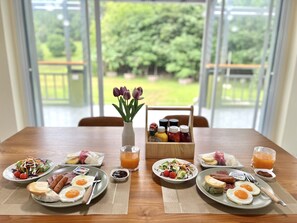 Una mesa de desayuno con diferentes platos, un florero con flores y condimentos.