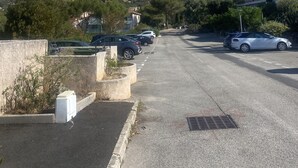 A parking lot with cars, a building with balconies, and a mountainous backdrop. - Petite Villa Attrayante vue mer Avec Jardin et Parking Privé (Saint-Raphaël)