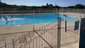A swimming pool surrounded by a metal fence, with a clear blue sky above. - Petite Villa Attrayante vue mer Avec Jardin et Parking Privé (Saint-Raphaël)