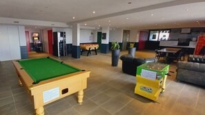 Ein Billardtisch, eine Couch und ein Kicker in der Hotelhalle.