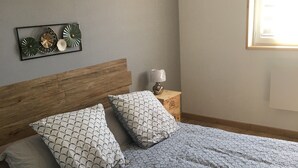 Una cama con ropa de cama estampada, un cabecero de madera y una mesita de noche con una lámpara.