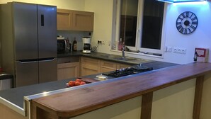 Una cocina moderna con una isla central, electrodomésticos de acero inoxidable, armarios de madera y un reloj de pared.