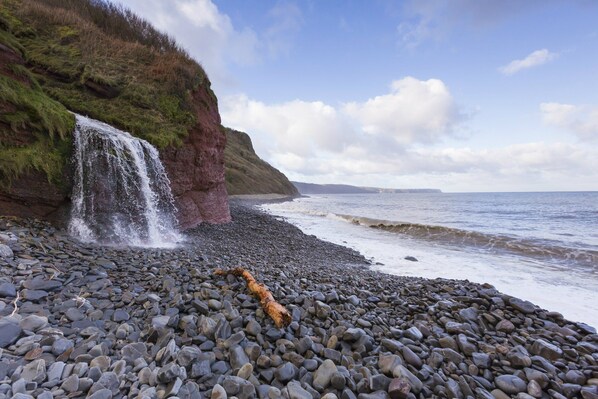 Experience the soothing sound of a waterfall cascading into a pebble beach.