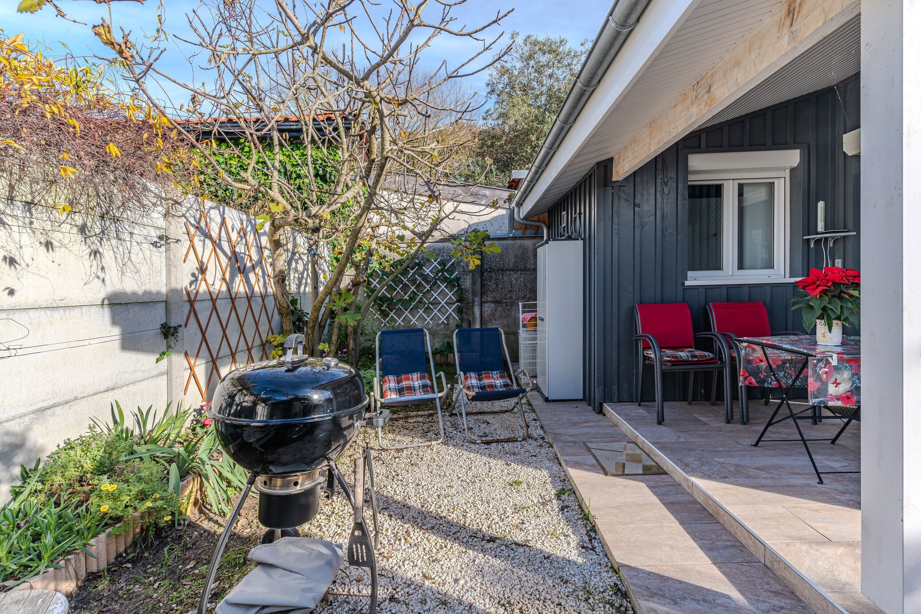 Un pati amb una barbacoa, mobiliari exterior i una petita zona de jardí.