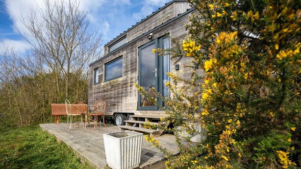 A modern wooden house with a deck, a bench, and a planter. - Tiny House 'Très Jolie Tout Confort' with Private Terrace, Private Garden and Wi-Fi (Prat)