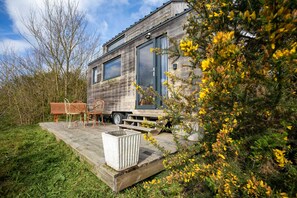 Une maison moderne en bois, dotée d’une terrasse, d’un banc et d’un jardinière.