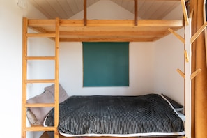 Una cama litera con escalera de madera, un tapiz azul turquesa y una ventana.