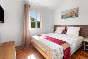 Une chambre à coucher avec un lit, une fenêtre avec des rideaux, un tableau au mur et un banc en bois.