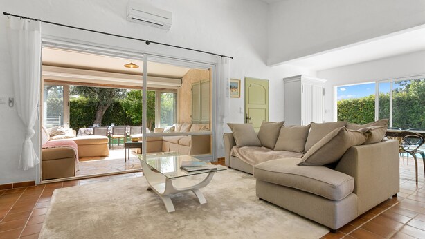 A living room with a glass coffee table, beige sofa, and a sliding glass door leading to an outdoor patio. - Villa "Norgreen 4" with Private Pool, Private Terraces and Wi-Fi (Grimaud)