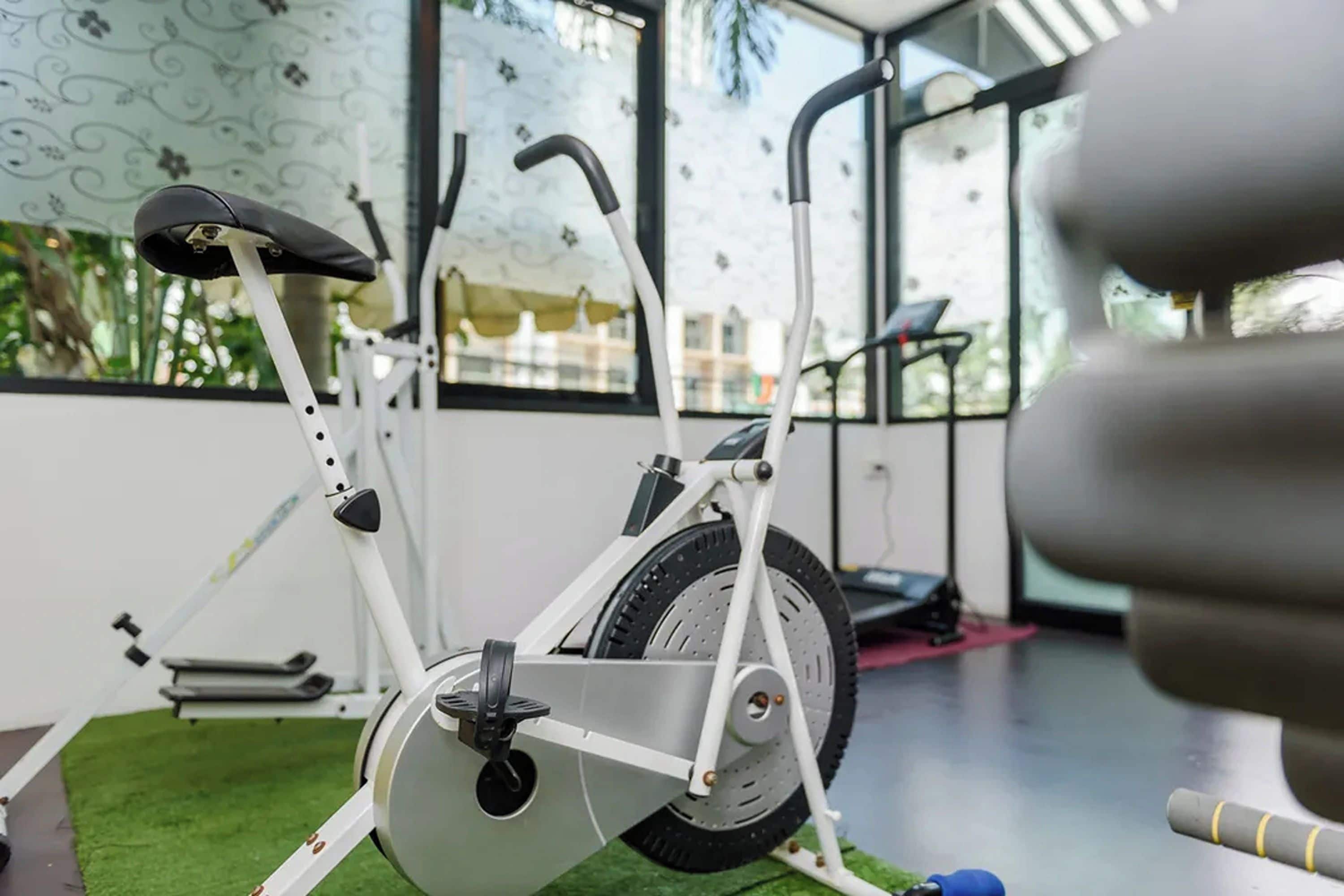 Un gimnasio interior con equipo de ejercicio, incluyendo una máquina elíptica y una cinta de correr.