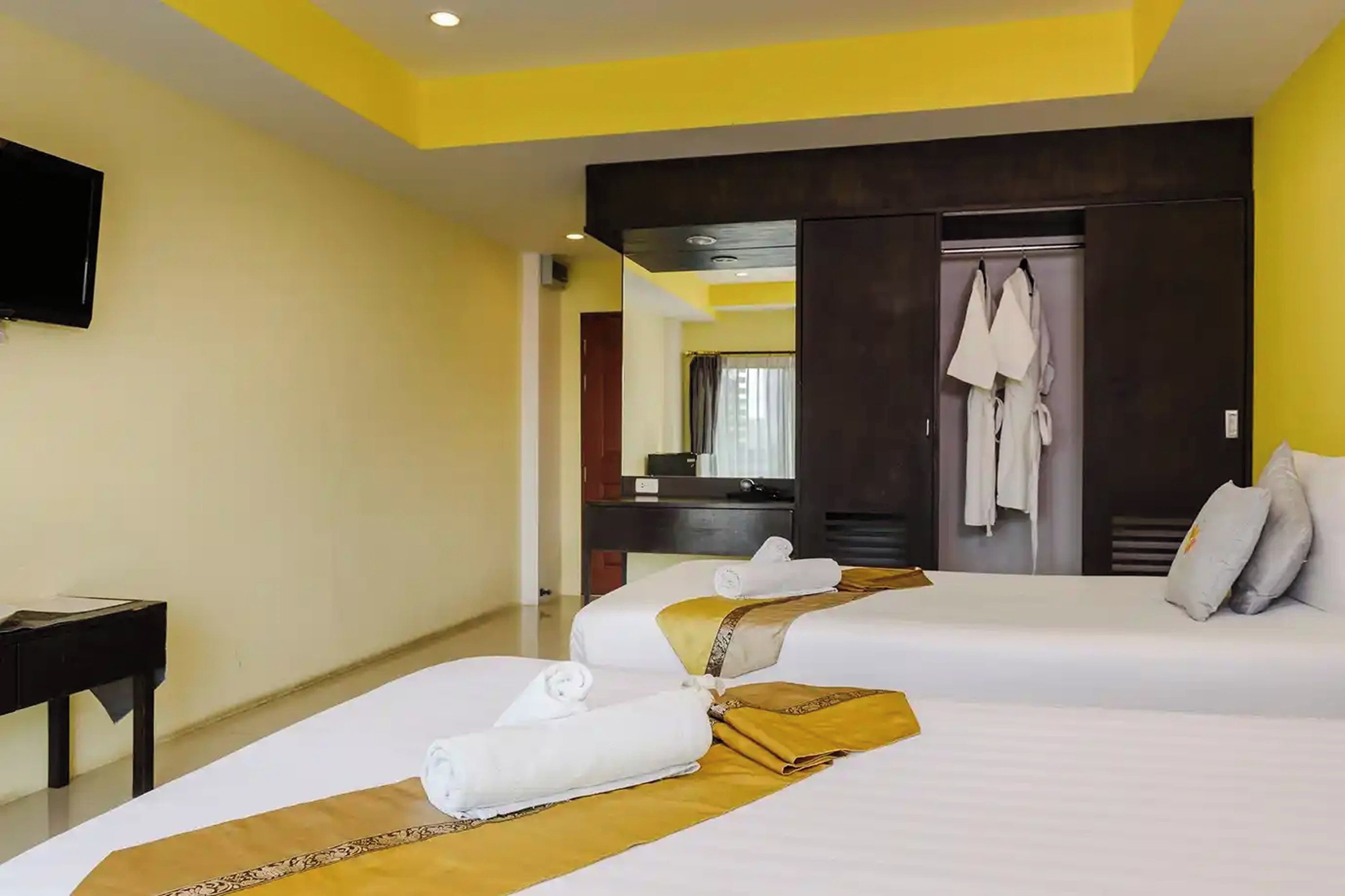 Une chambre d’hôtel avec deux lits, une télévision et une salle de bain visible à travers une porte ouverte.