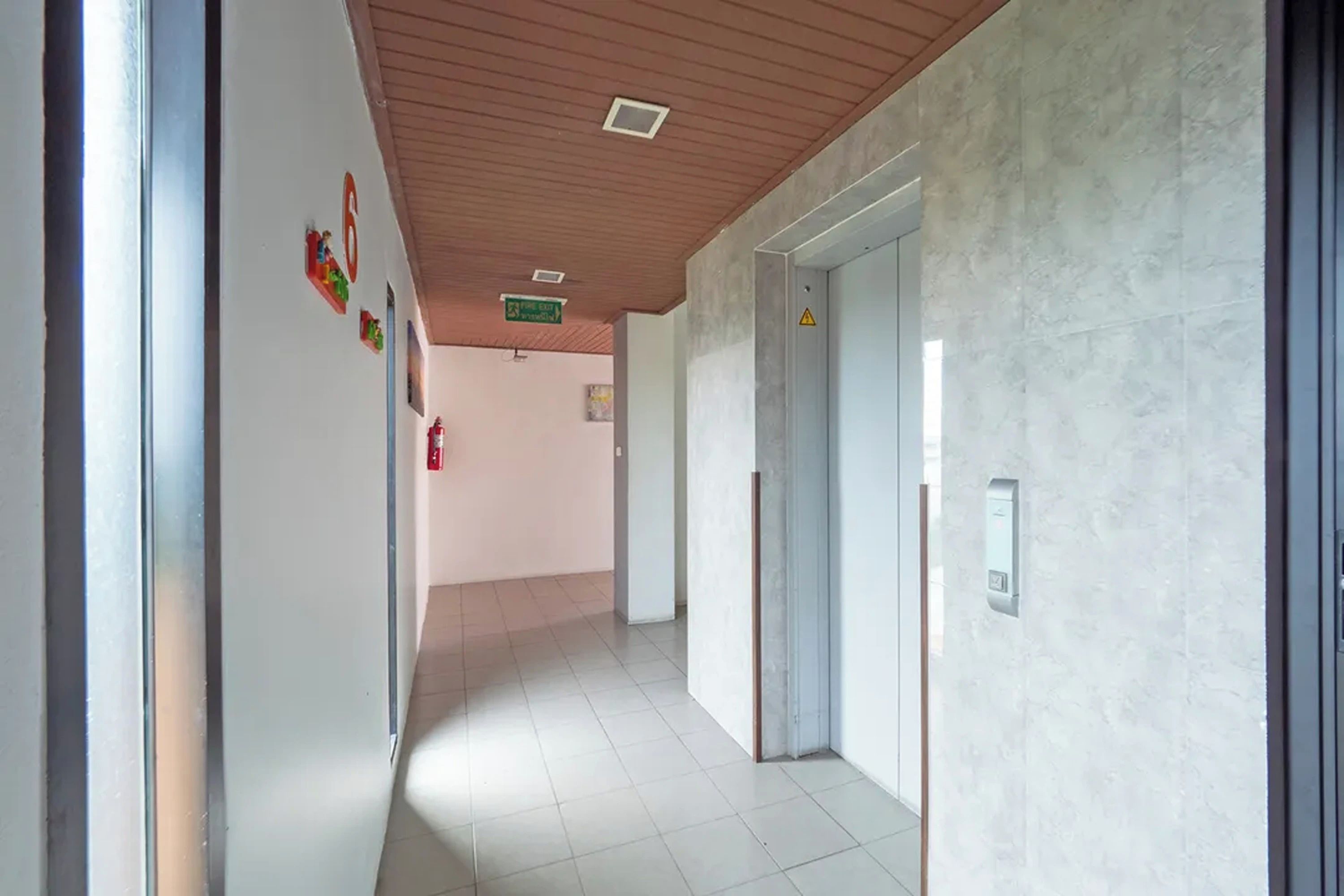 Un pasillo con un letrero de salida de incendios, un detector de incendios y una puerta con un panel de seguridad.