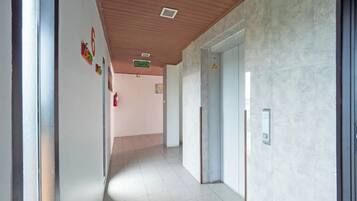 Un pasillo con un letrero de salida de incendios, un detector de incendios y una puerta con un panel de seguridad.