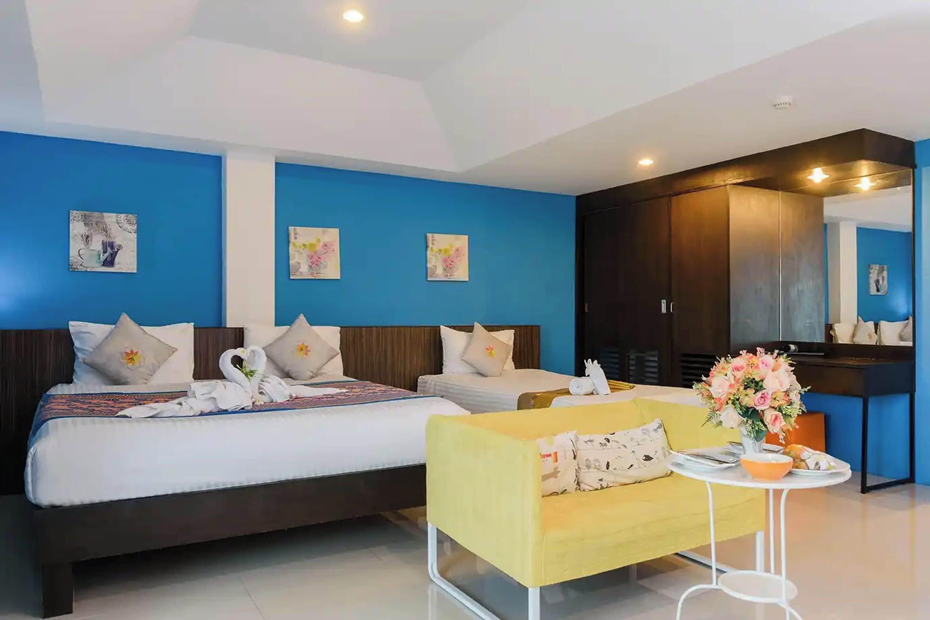 Una habitación de hotel con una cama grande, un sofá y una pequeña mesa con un florero.