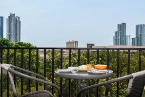 A balcony with a table set for breakfast, overlooking a cityscape with high-rise buildings. - Stay Resort Pattaya (Pattaya)