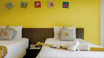 Habitación de hotel con dos camas, una mesita de noche con un jarrón de flores y una pared decorada con obras de arte de colores.