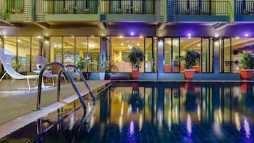 Una piscina al aire libre, sombrillas, sillones reclinables de piscina