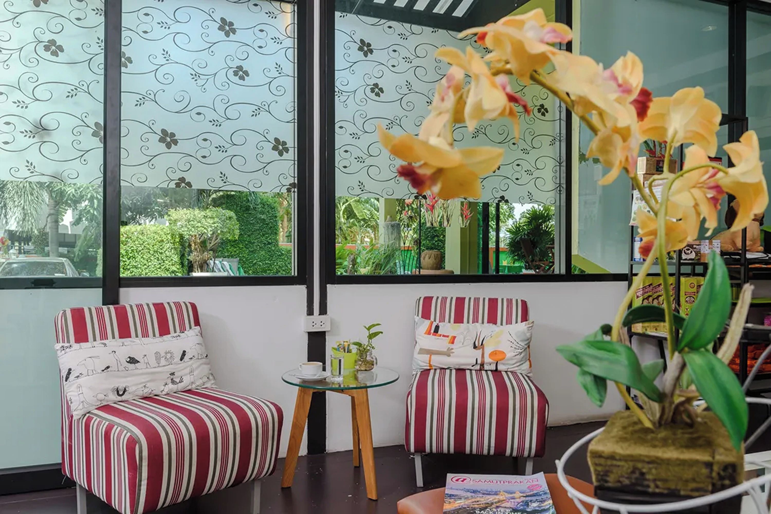 Una habitación con dos sillas a rayas, una mesita pequeña y un ventanal con vistas a zonas verdes.