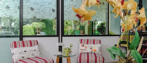 A room with two striped chairs, a small table, and a large window with a view of greenery outside.