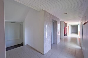 A spacious corridor with white walls and a tiled floor, leading to multiple rooms. - Stay Resort Pattaya (Pattaya)