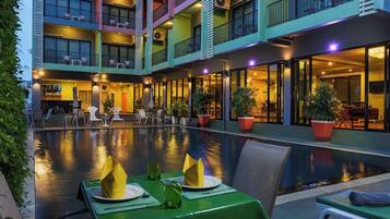 Um hotel com vários andares, piscina, área de estar externa e varandas.