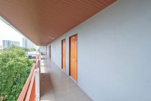 A corridor with a tiled floor, wooden doors, and a balcony with a railing. - Stay Resort Pattaya (Pattaya)
