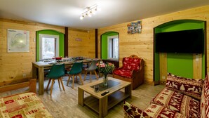 Ein Holzambiente mit Essbereich, einer Couch, einem Fernseher und einer Karte an der Wand.