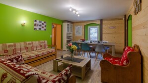 Ein Zimmer mit einer Couch, einem Esstisch mit Stühlen, einer Küchenzeile und einer Holzwand mit einem Schild.