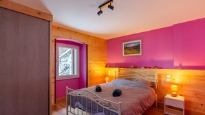 Ein Schlafzimmer mit Bett, Nachttisch, Fenster und Holzwänden.