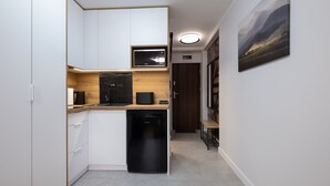 Una cocina compacta con armarios blancos, lavavajillas negro y microondas.