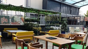 An outdoor cafe with wooden tables and chairs, a glass roof, and potted plants. - Myra Residences by Extended Stays 2 Bedrooms (Nairobi)