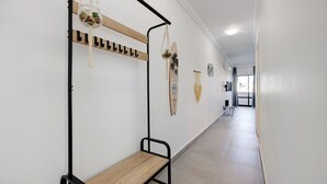Un pasillo con un banco, perchero y adornos de pared que incluyen una tabla de surf y una planta.