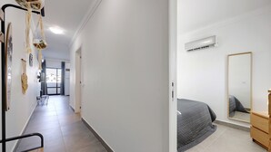 Un pasillo con una cama, cómoda y espejo en un dormitorio.