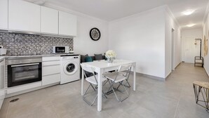 Una cocina moderna con electrodomésticos integrados, un comedor con mesa y sillas blancas y una lavadora.