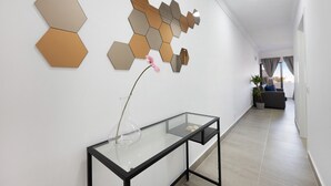 A modern interior with a glass console table, a decorative wall panel, and a potted plant. - Apartment "Victoria's House" with Shared Pool & Wi-Fi (Sagres)