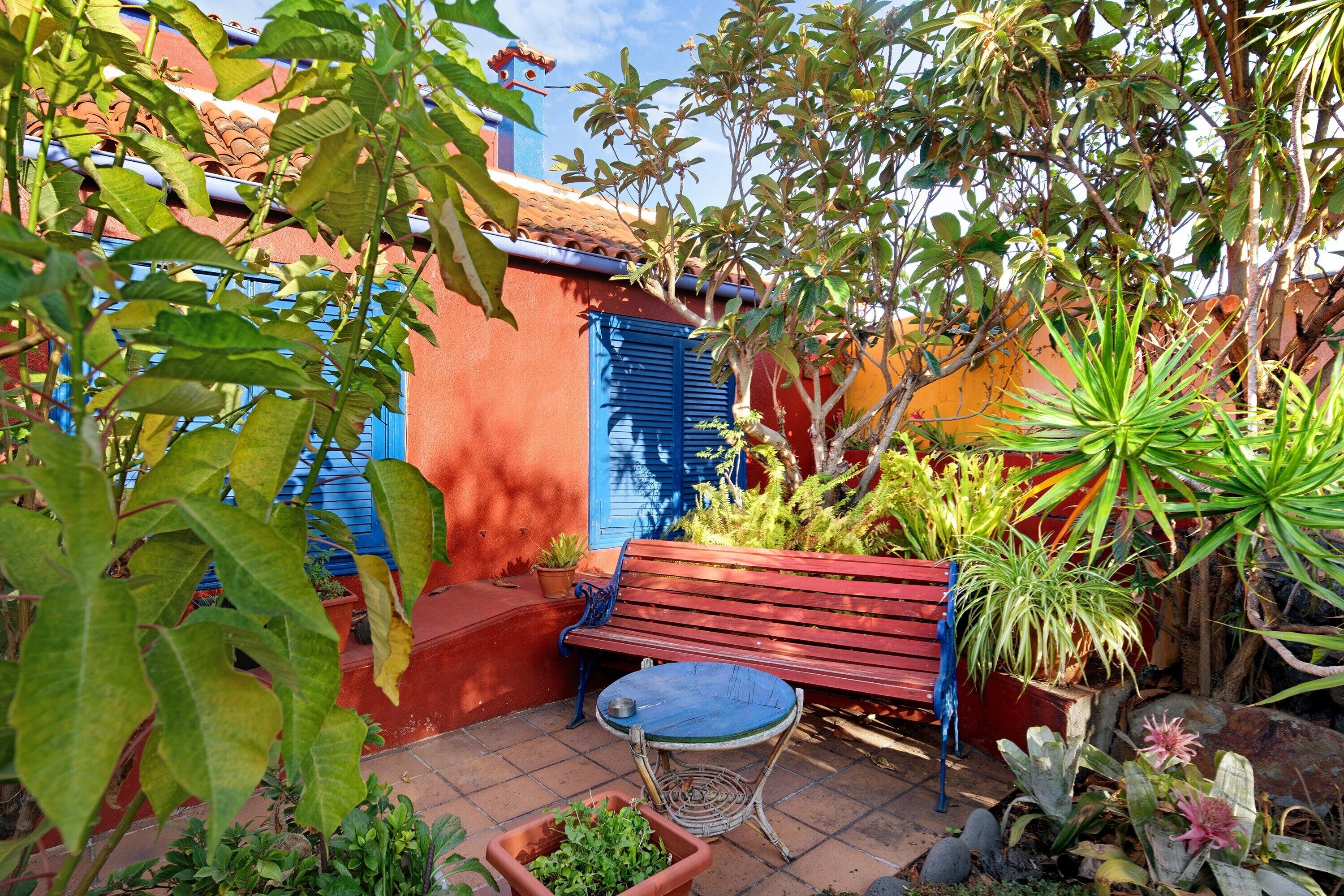 A patio with a bench, potted plants, and a tiled floor.