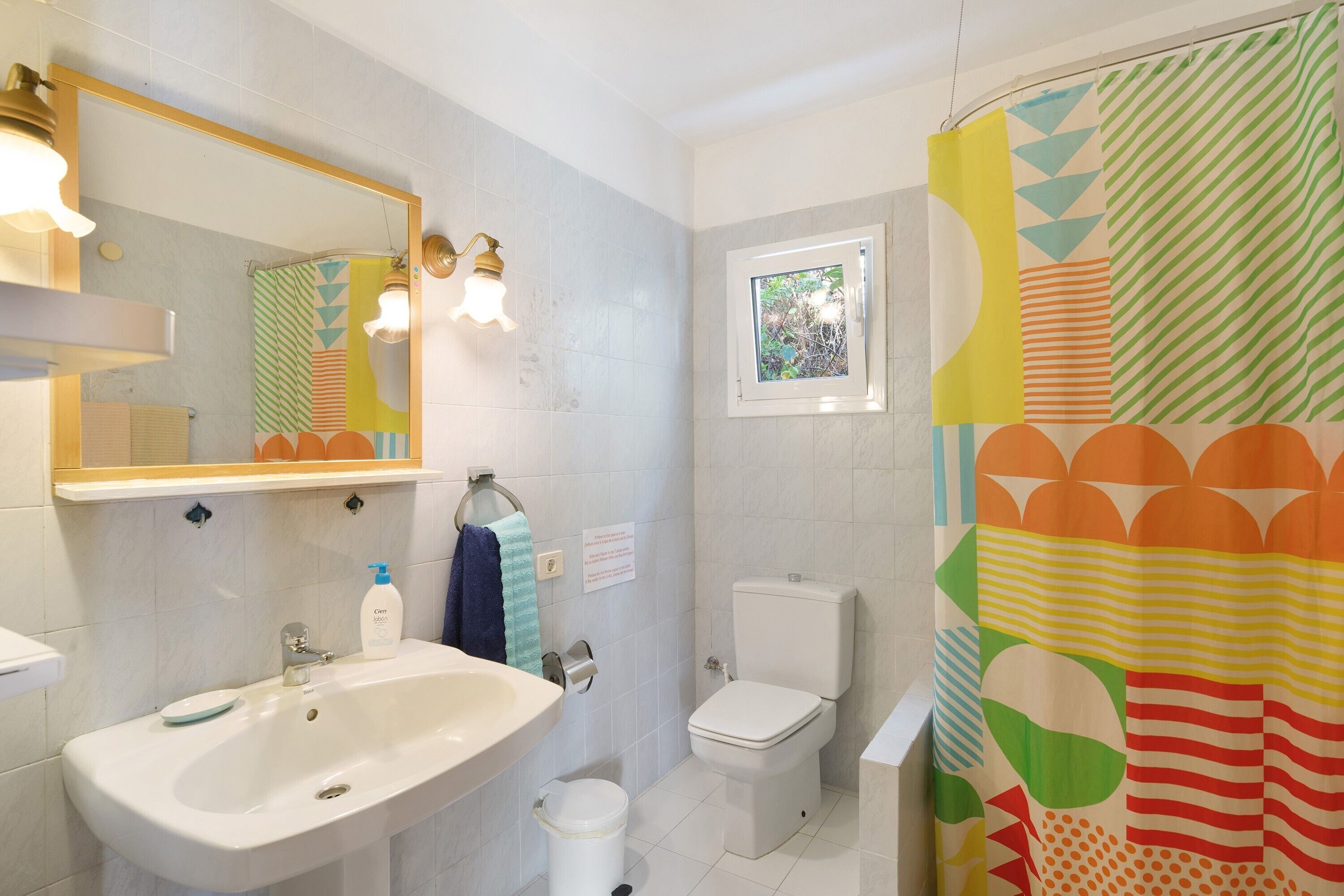 Un baño con lavamanos, inodoro y cortina de ducha.